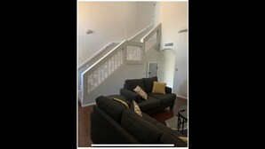 Un salon avec un escalier, un ensemble de canapés et une petite table.