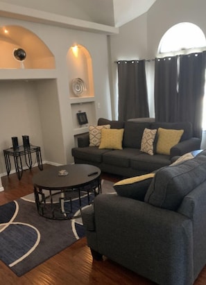 Un salon avec un canapé gris, une table basse ronde et un tapis à motifs.
