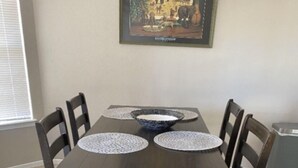 Une table de salle à manger rectangulaire à la finition sombre, quatre chaises et deux grands bols posés sur des sets de table.