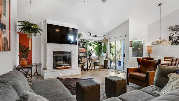 Un salon moderne avec une cheminée, des canapés gris et un coin repas comprenant une table et des chaises.