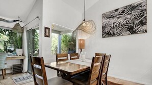 Un coin repas avec une table et des chaises en bois, un luminaire suspendu et une lampe fixée au mur.