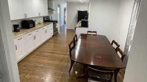 A modern kitchen with white cabinets, a wooden dining table, and a refrigerator. - Charming home with a pool (Michigan City)