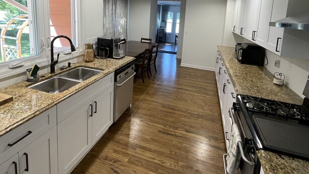 A modern kitchen with granite countertops, stainless steel appliances, and wooden flooring. - Charming home with a pool (Michigan City)