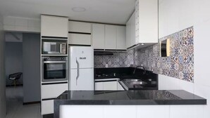 Eine moderne Küche mit weißen Schränken, einer schwarzen Arbeitsplatte und einer gemusterten Spritzschutzwand.