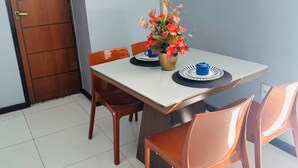 Ein Essbereich mit Tisch, Stühlen, einer Blumenvase und einer Hängelampe.