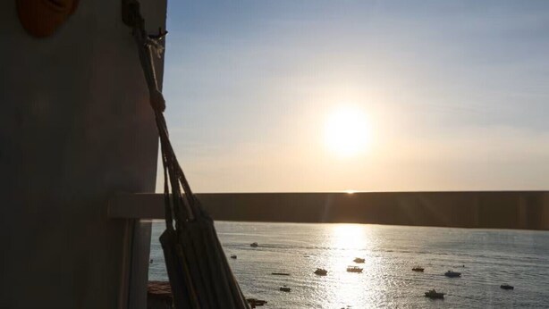 Sonnenuntergangblick von einem Balkon mit Geländer und klarem Himmel.
