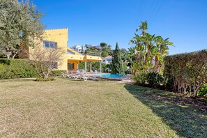 A modern yellow building with a pool, surrounded by well-maintained grass and trees. - Luxury Villa with spectaculair views Varenso Holidays (Marbella)