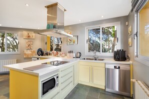 A modern kitchen with a central island, stainless steel appliances, and a large window providing natural light. - Luxury Villa with spectaculair views Varenso Holidays (Marbella)