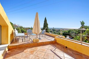 A rooftop terrace with a yellow wall, tiled flooring, and outdoor furniture including chairs and a table. - Luxury Villa with spectaculair views Varenso Holidays (Marbella)