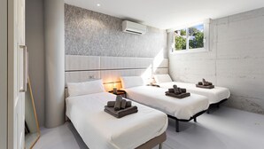 Una habitación de hotel moderna con dos camas, un ventanal grande y un aire acondicionado de pared.