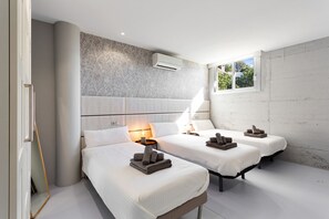 A modern hotel room with two beds, a large window, and a wall-mounted air conditioner. - Luxury Villa with spectaculair views Varenso Holidays (Marbella)