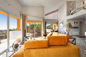 Ein geräumiger Wohnbereich mit einer großen Couch, einem Esstisch und einem Balkon mit Gartenmöbeln.