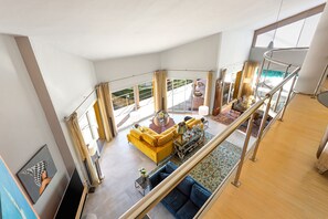 A spacious living area with a yellow sofa, a coffee table, and a view of the outdoor patio.