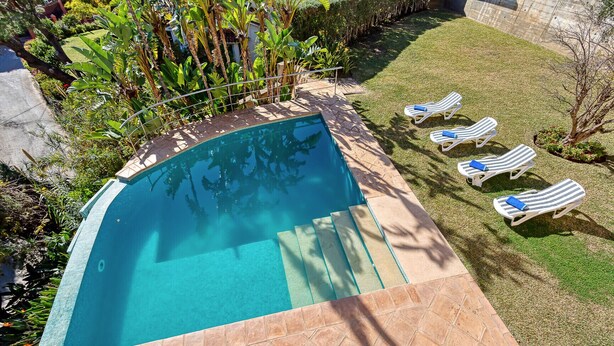 Una piscina con solárium y sillones de relax.