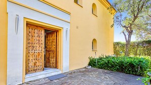 Un edificio con puerta de madera, entrada empedrada y una ventana pequeña.