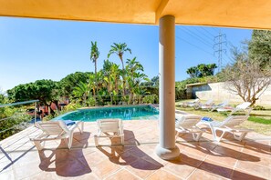An outdoor pool area with lounge chairs and a covered patio.