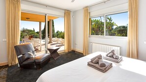 Una habitación de hotel con cama, una silla, una mesa, una ventana que da a zonas verdes y un ventilador de techo.