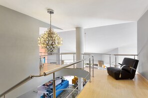 Un interior moderno con una escalera, un sillón de cuero negro y un candelabro decorativo.