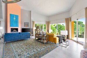 Ein geräumiges Wohnzimmer mit einem blauen Sofa, einem gelben Sessel und einem gemusterten Teppich.