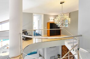 Ein modernes Interieur mit einer Wendeltreppe, einem Chandelier und Blick auf den Wohnbereich.
