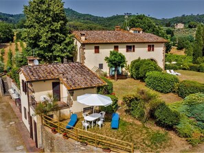 A villa with a tiled roof, a patio with a table and chairs, and a small garden with a lawn and a tree. - Stunning  villa for 16 guests with private pool, WIFI, TV, patio, pets allowed and panoramic view (Scandicci)