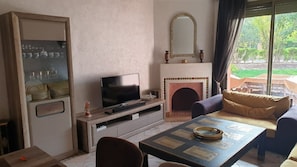 Una sala de estar con televisor, chimenea, sofá y una mesa de centro.