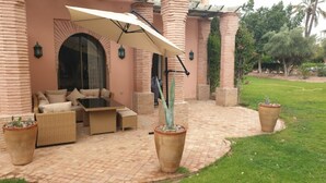 An outdoor patio with a seating area, a large umbrella, and potted plants.