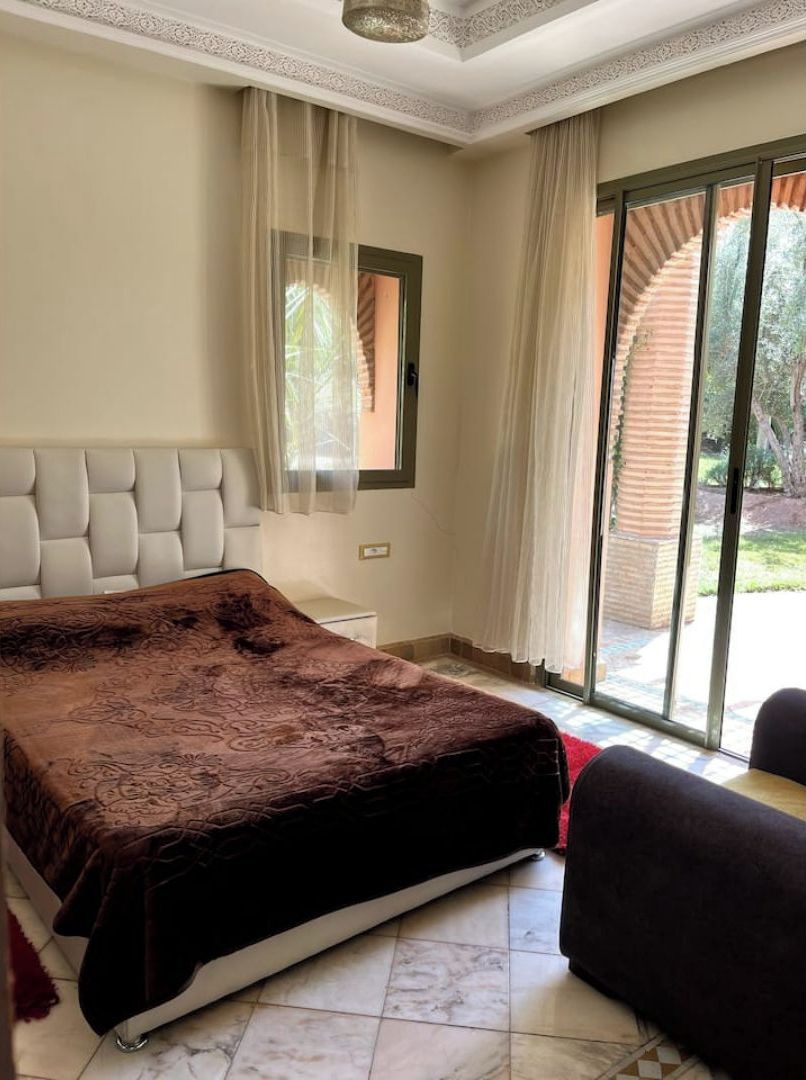 Une chambre avec un grand lit, une fenêtre avec des rideaux et une vue sur l’extérieur.