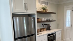 Une cuisine moderne avec des meubles blancs, un réfrigérateur en acier inoxydable, un four à micro-ondes et un plancher en bois.