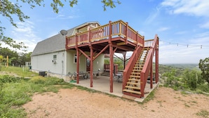 A house with a wooden deck and a staircase leading to a second-story balcony.
