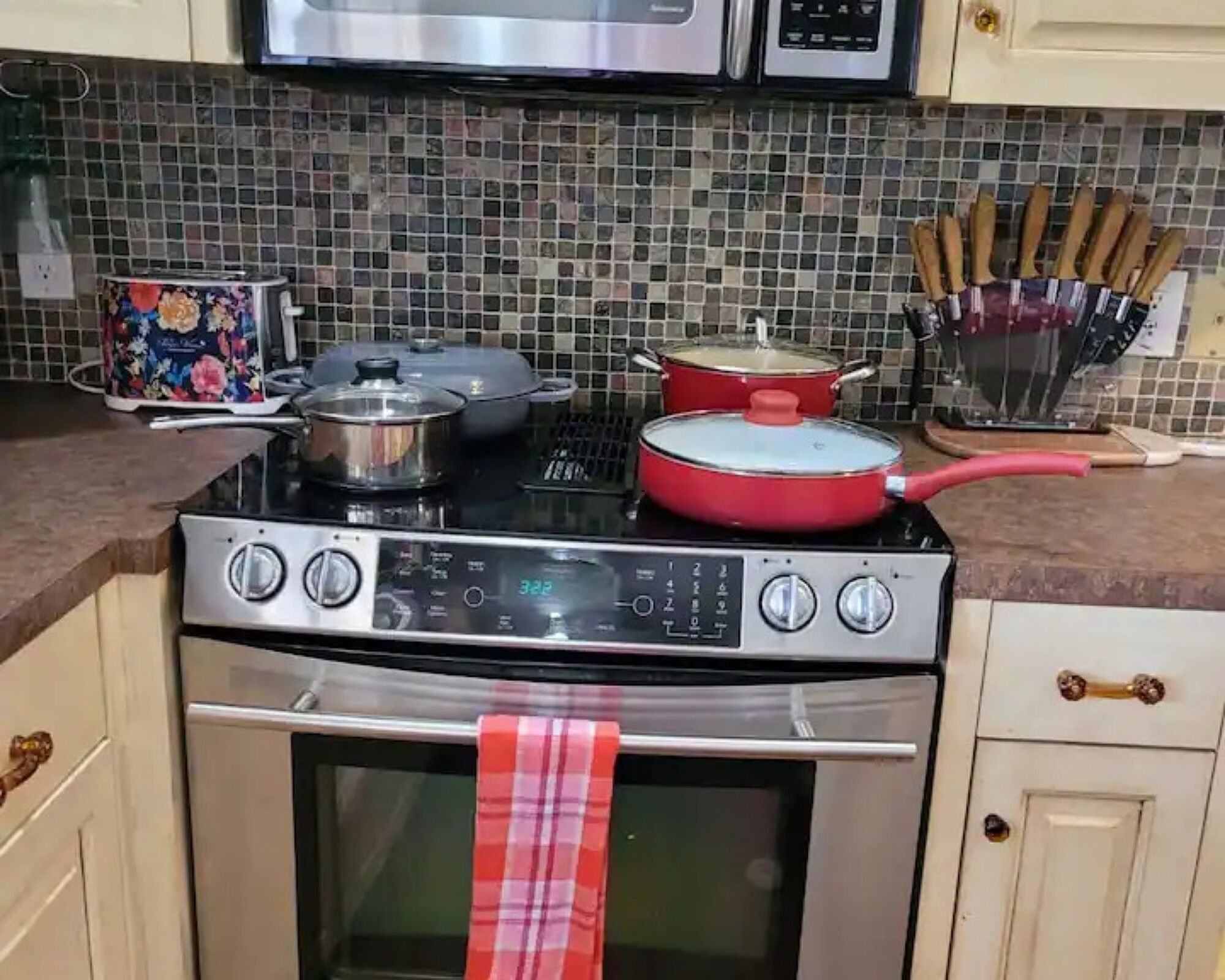 A kitchen with a stove, pots, a microwave, and a set of knives.
