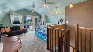 A spacious living area with a ceiling fan, a wooden bench, a sofa, and a colorful bedspread.