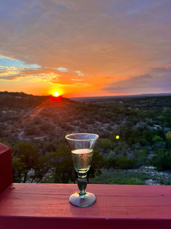 A glass of water on a wooden surface with a sunset view in the background.