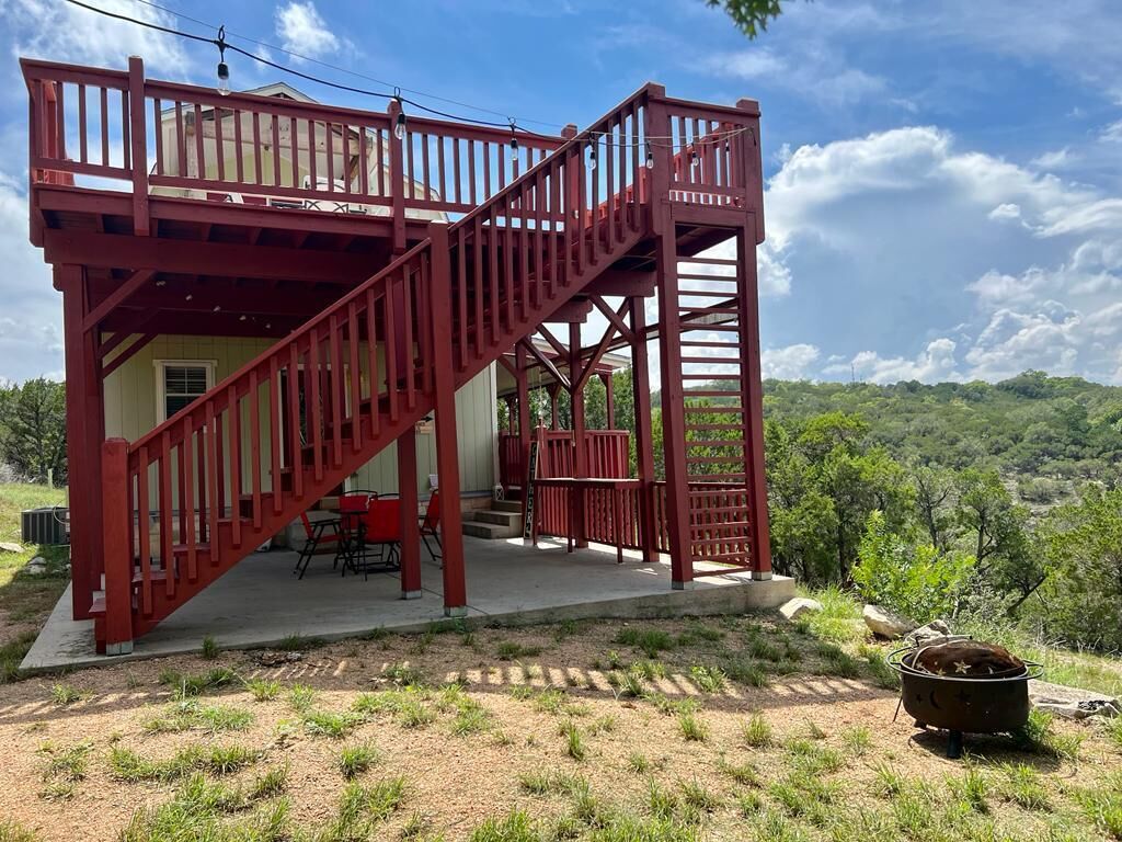 A red wooden staircase leading to a covered outdoor area with a table and chairs.