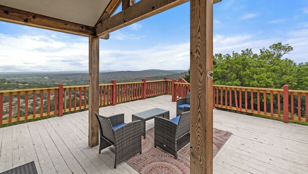A wooden deck with outdoor furniture and a view of the landscape.