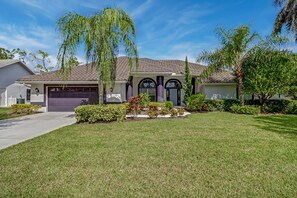 A two-story house with a tiled roof, a garage, and a well-maintained lawn.