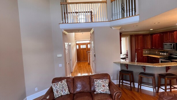 A spacious living room with a brown leather sofa, a patterned rug, and a ceiling fan. - Executive Home on over an Acre of Land.  Country Living at its Best. (Youngsville)