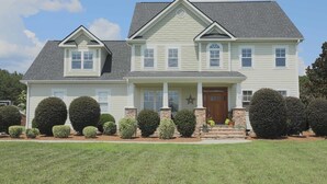 A two-story house with a front porch, a star decoration, and a well-maintained lawn. - Executive Home on over an Acre of Land.  Country Living at its Best. (Youngsville)
