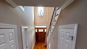 A hallway with wooden flooring, white doors, and a staircase with a railing. - Executive Home on over an Acre of Land.  Country Living at its Best. (Youngsville)