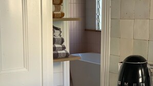 Une cuisine avec un plan de travail blanc, une machine à café noire et un meuble en bois.