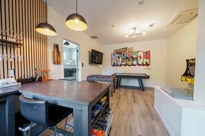 A modern living room with a pool table, foosball table, and a wall with a 'Welcome to' sign.