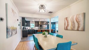 Una cucina moderna con mobili scuri, un'isola centrale e un'area da pranzo con un tavolo in legno e sedie blu.