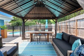 A covered patio with a pool, outdoor furniture, and a view of the backyard.