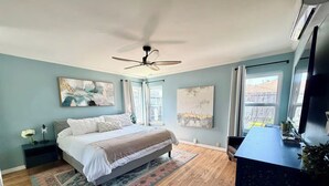 Una camera da letto con un letto, comodini, una scrivania e una ventola a soffitto.