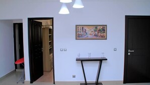 A room with a door, a table with two vases, and a painting on the wall. - Résidence Clean (Abidjan)