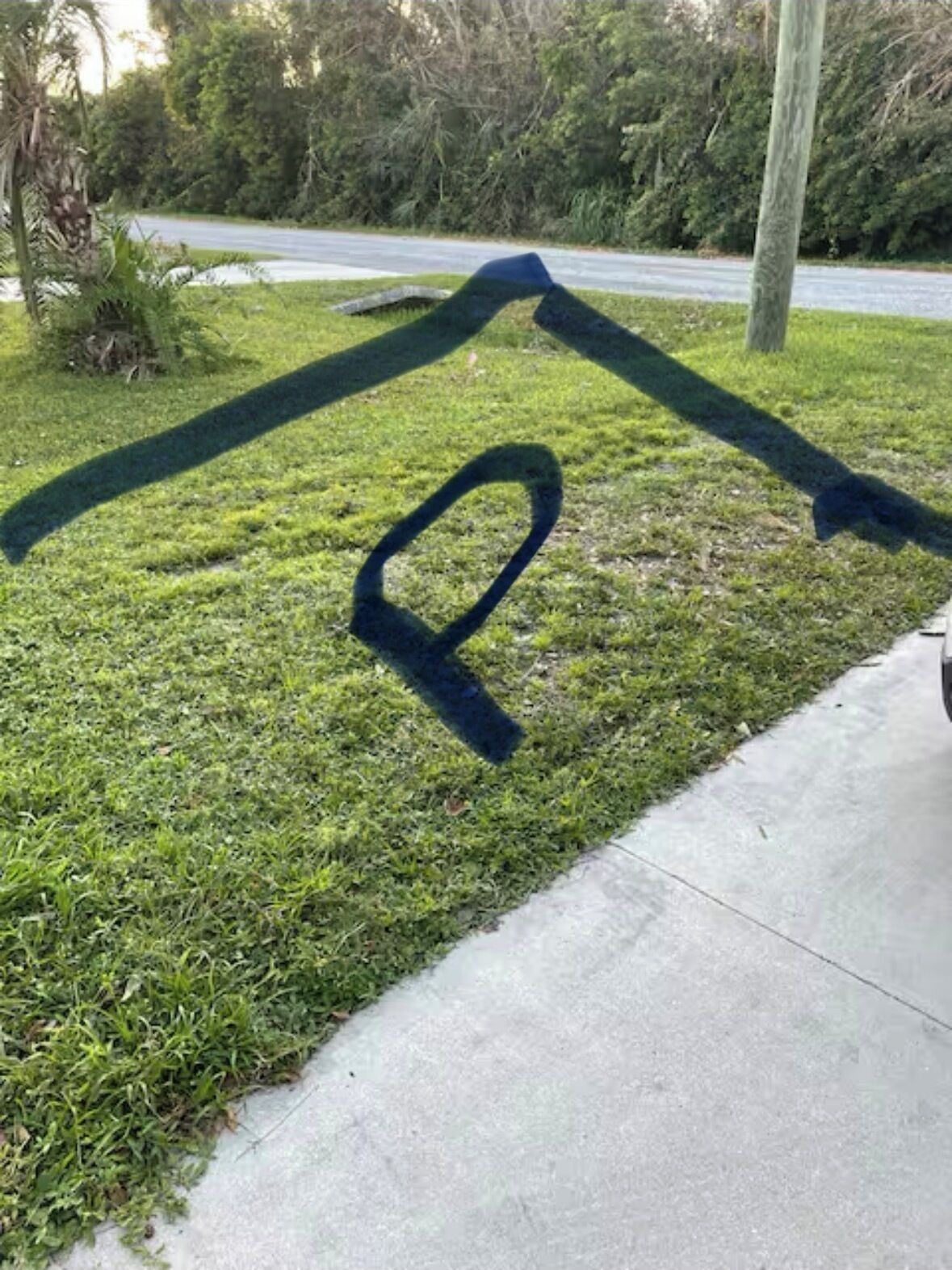 A grassy area with a concrete path and a road in the background.
