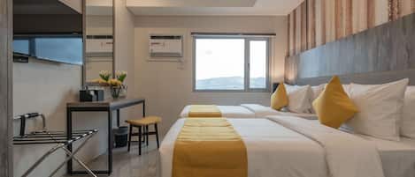 A hotel room with a bed, a desk, a chair, a mirror, and a window.
