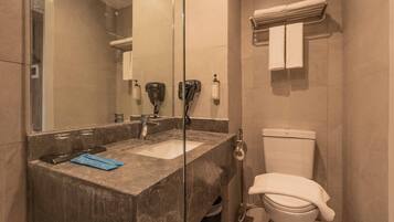 A bathroom with a marble sink, a glass shower enclosure, a toilet, and a towel rack.