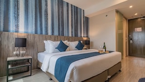 A modern hotel room with a large bed, a nightstand, a wall-mounted lamp, and a wooden headboard. - Bayfront Hotel Cebu - Capitol Site (Cebu City)