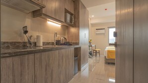 A modern kitchen with wooden cabinets, a stainless steel sink, and a microwave. - Bayfront Hotel Cebu - Capitol Site (Cebu City)